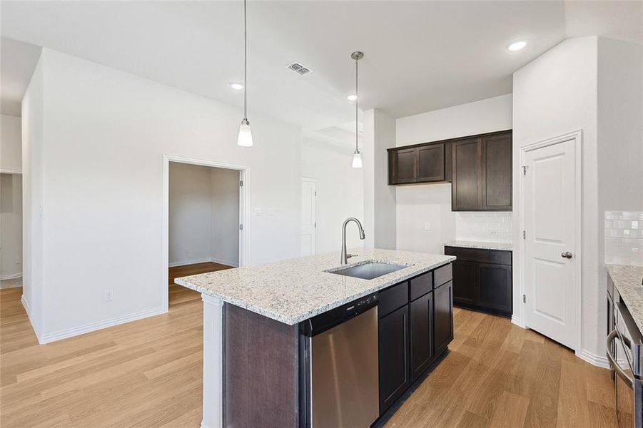 Kitchen with sink, decorative backsplash, light wood-type flooring, and dishwasher