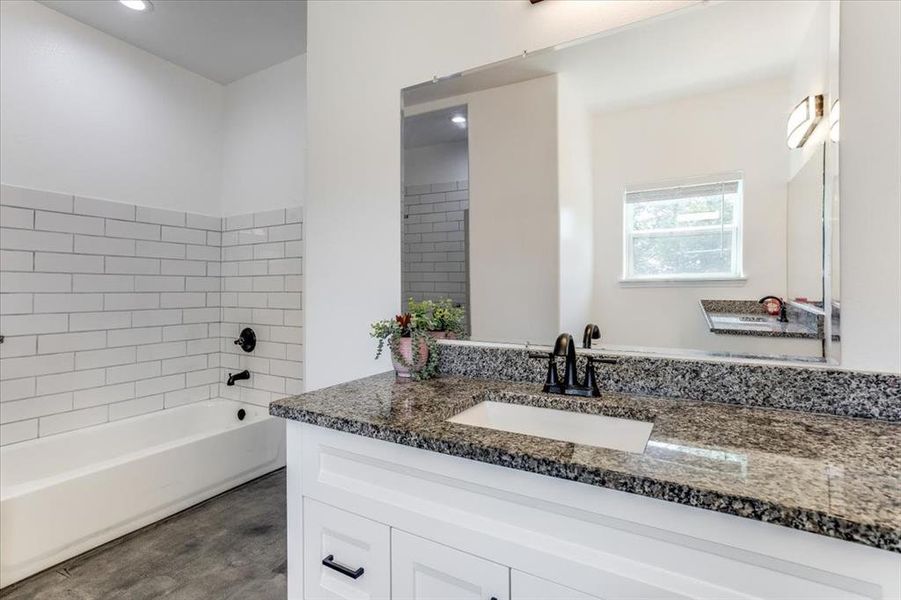Bathroom vanity featuring a speckled countertop, undermount sink, and black faucet
