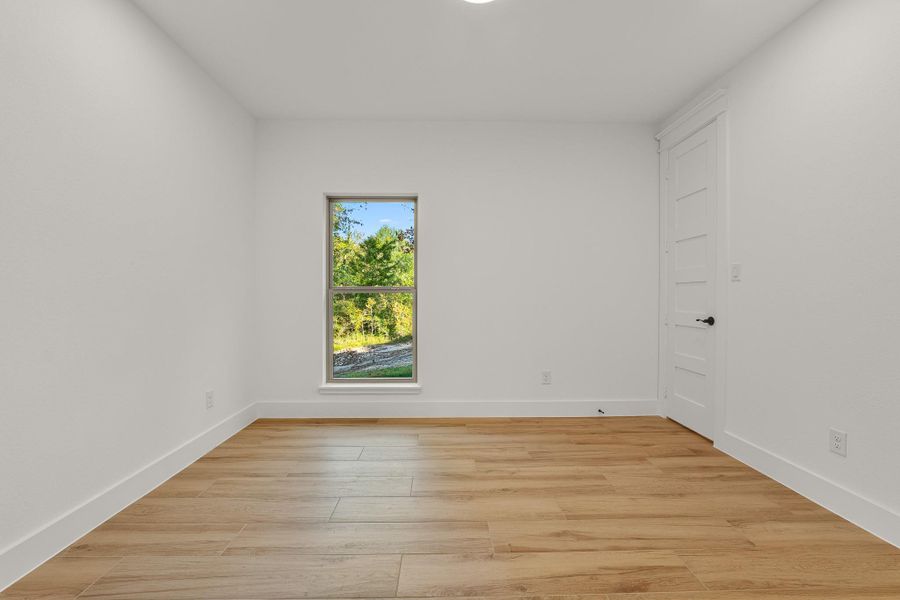 This room features a bright and airy space with light wood flooring, a single window offering a view of greenery, and a white door. Perfect for a bedroom or office. This room features a bright and airy space with light wood flooring, a single window offering a view of greenery, and a white door. Perfect for a bedroom or office.