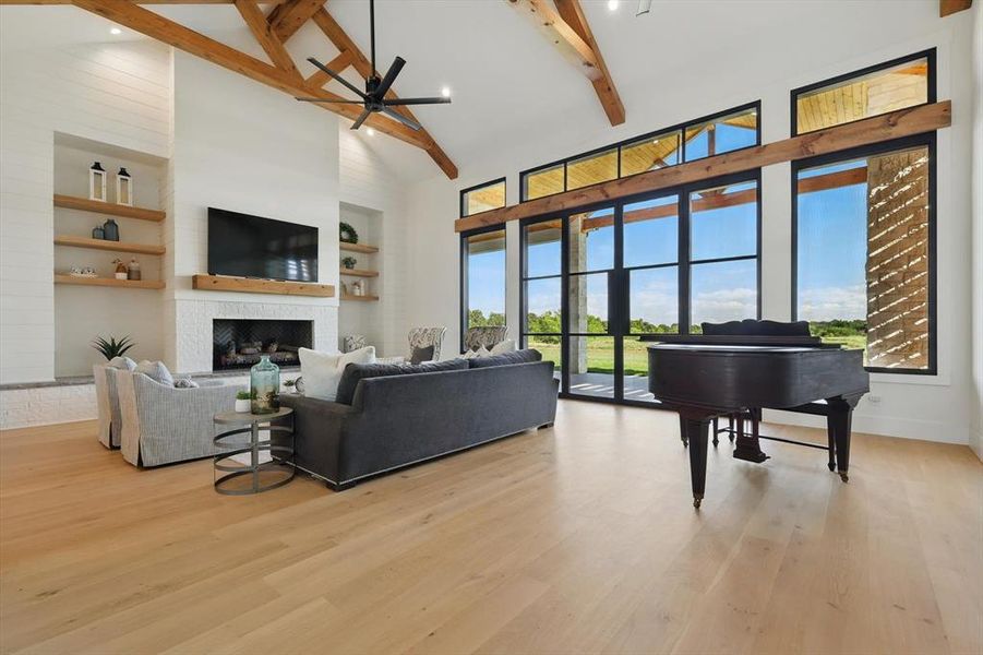 Living room featuring high vaulted ceiling, a fireplace, beamed ceiling, ceiling fan, and wood finished floors Living room featuring high vaulted ceiling, a fireplace, beamed ceiling, ceiling fan, and wood finished floors
