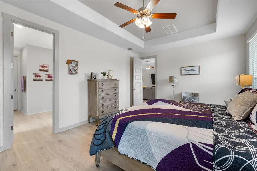 Bedroom with a raised ceiling, wood finished floors, and a ceiling fan Bedroom with a raised ceiling, wood finished floors, and a ceiling fan