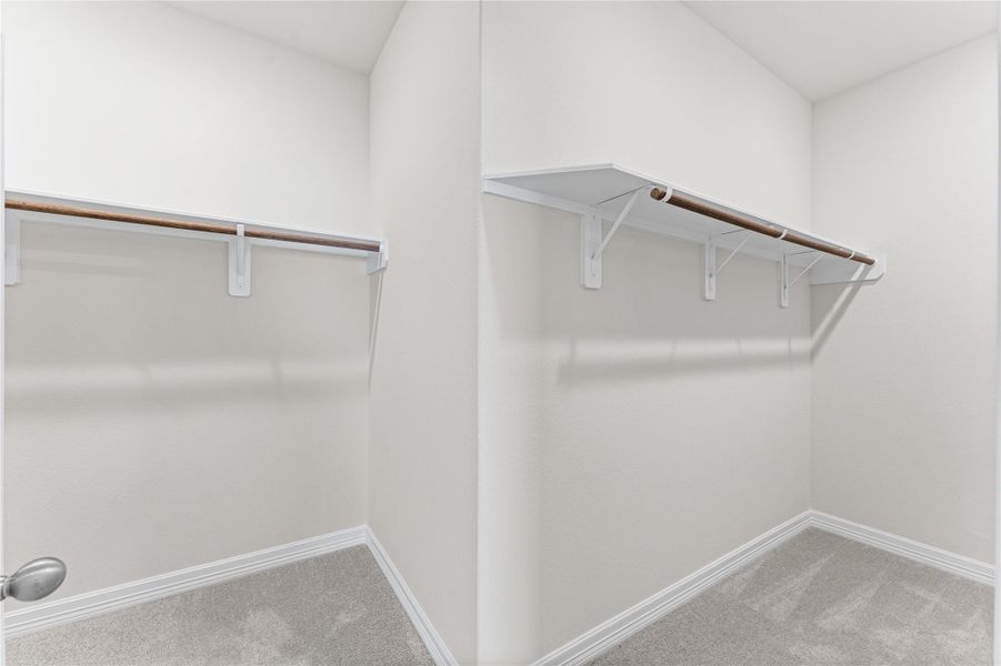 Primary walk-in closet with custom shelving and generous storage space. Primary walk-in closet with custom shelving and generous storage space.