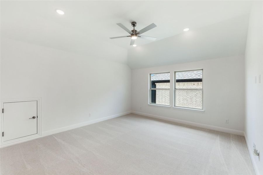 Empty bedroom with vaulted ceiling, ceiling fan, carpet flooring, and two windows