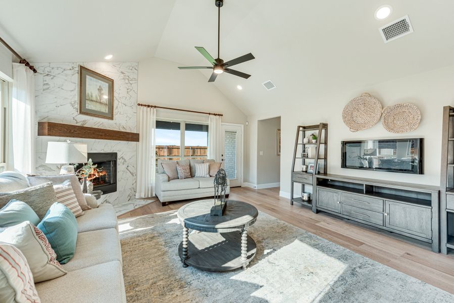 Living room with vaulted ceiling, marble fireplace, hardwood floors, and ceiling fan