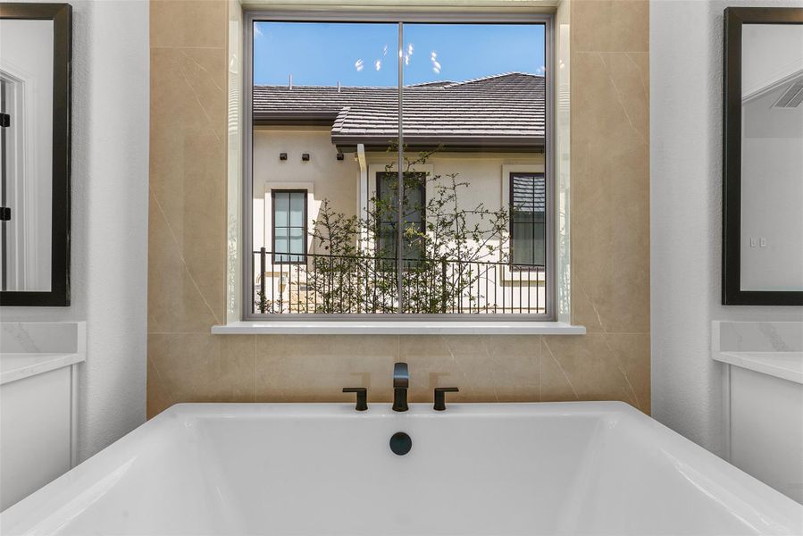 The bathroom features a large soaking tub with a modern faucet, set against a tiled wall