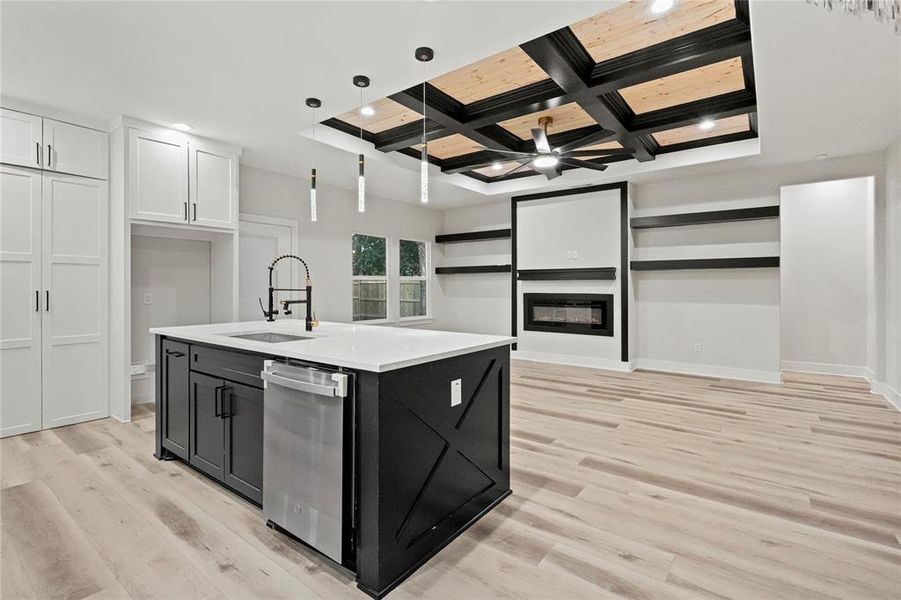 Kitchen with sink, coffered ceiling, an island with sink, white cabinets, and light wood-type flooring