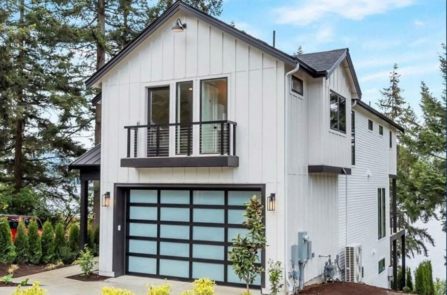 View of front of property featuring board and batten siding, a balcony, and an attached garage
