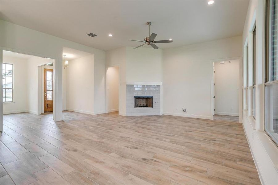 Unfurnished living room featuring light wood-type flooring, a fireplace, and ceiling fan