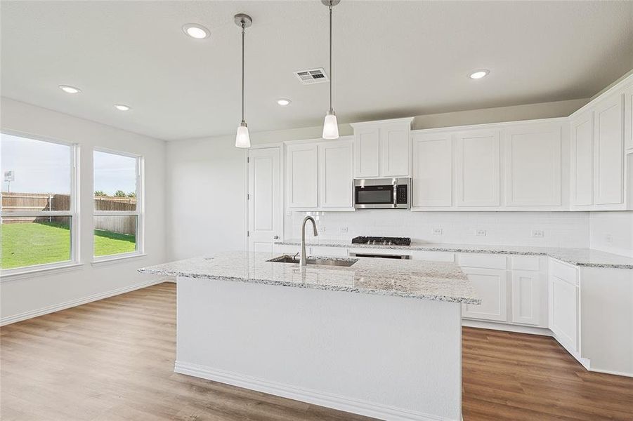 Kitchen with sink, appliances with stainless steel finishes, white cabinetry, and an island with sink