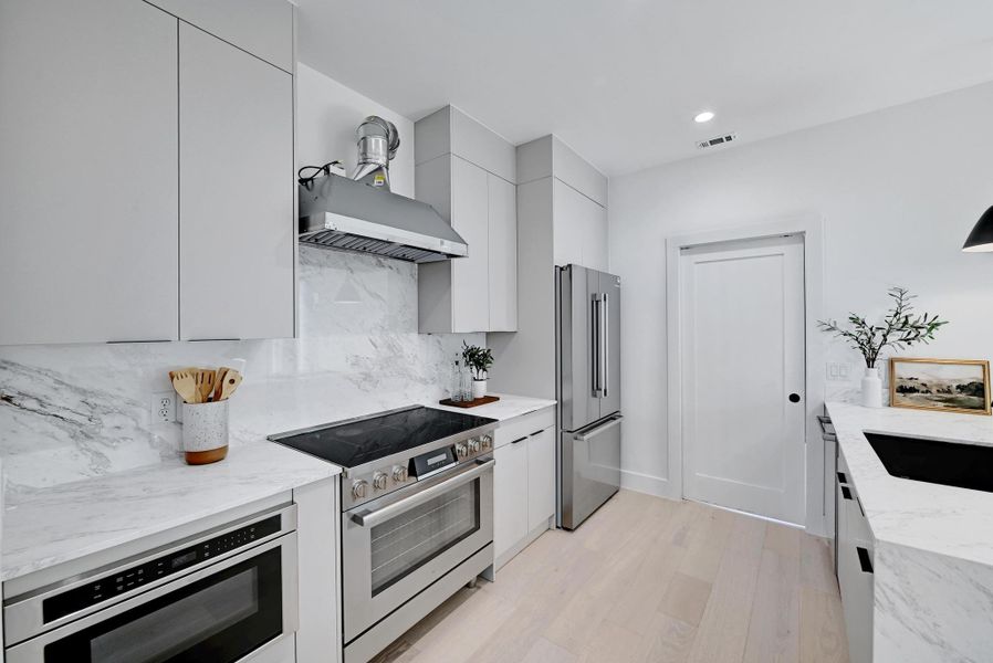 Kitchen with light quartz countertops, modern cabinets, and appliances with stainless steel finishes