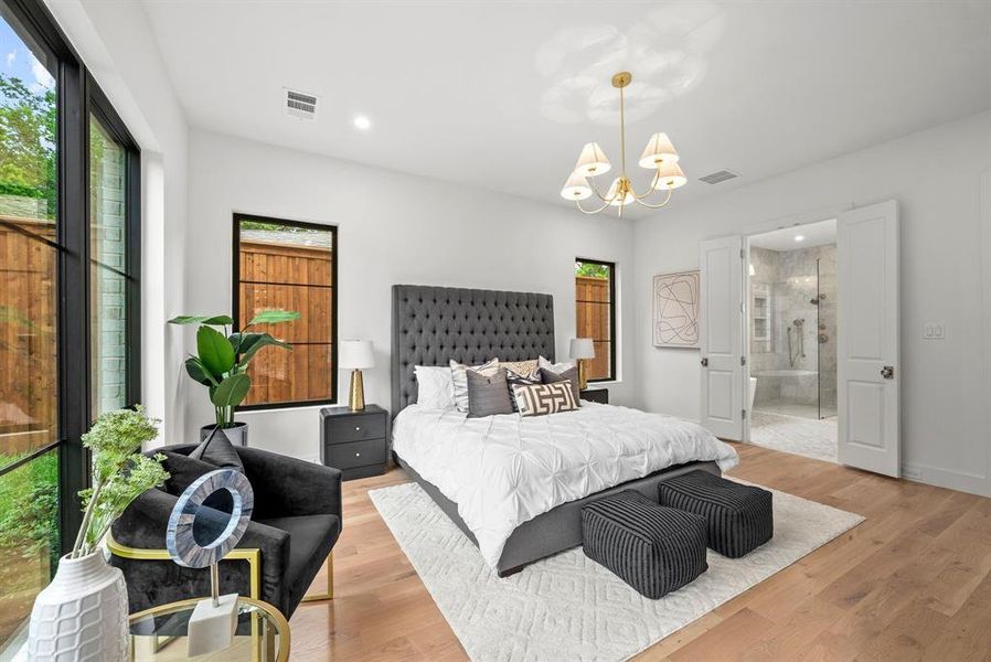 This room features light hardwood flooring, a contemporary chandelier, and large windows with black frames