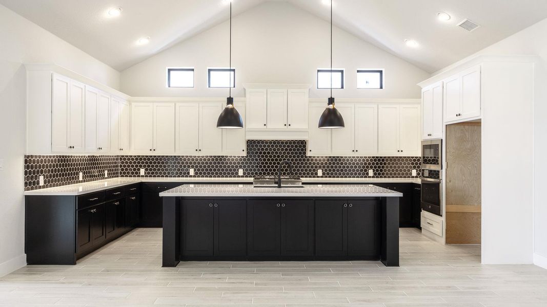 Kitchen featuring dark cabinetry, pendant lighting, tasteful backsplash, white cabinetry, and high vaulted ceiling