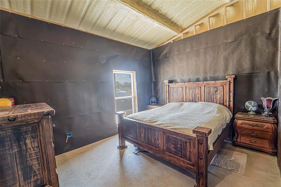 Bedroom with vaulted ceiling and concrete floors
