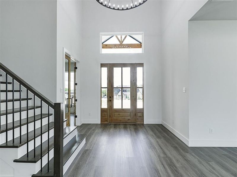 Step through the stunning mahogany extra-wide glass door with dual sidelights into a foyer that soars 20 feet high, illuminated by a striking chandelier