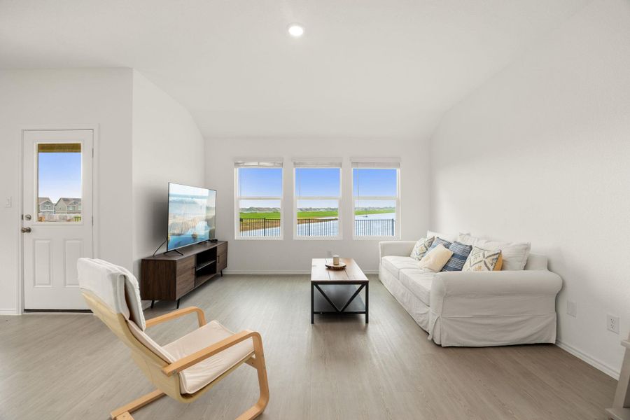 A tranquil living space with generous windows offers picturesque views of a nearby lake and verdant landscape.