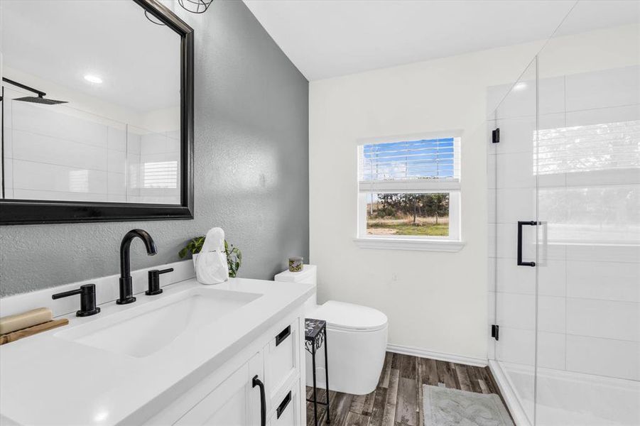 Bathroom with vanity, a stall shower, dark wood finished floors, and a textured wall