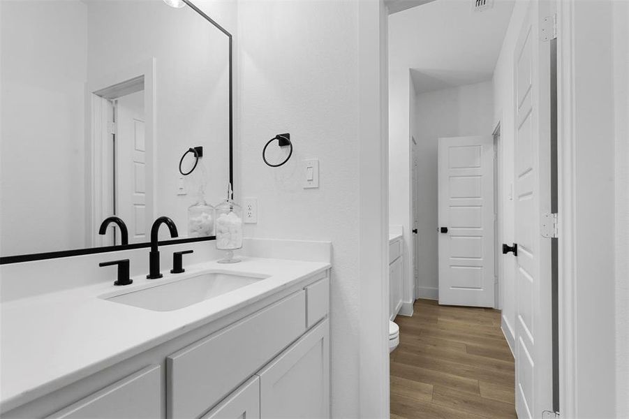 Bathroom with hardwood / wood-style floors, vanity, and toilet