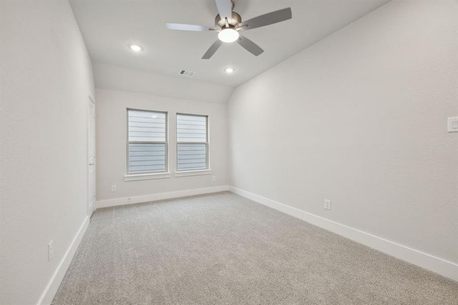 Empty room with lofted ceiling, ceiling fan, and carpet flooring