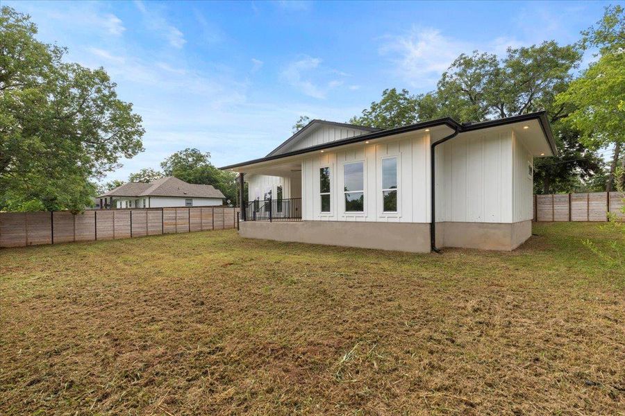 Rear view of house with a fenced backyard and board and batten siding Rear view of house with a fenced backyard and board and batten siding