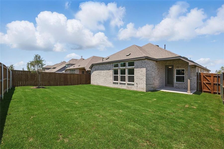 Rear view of house with a patio area, brick siding, and roof with shingles
