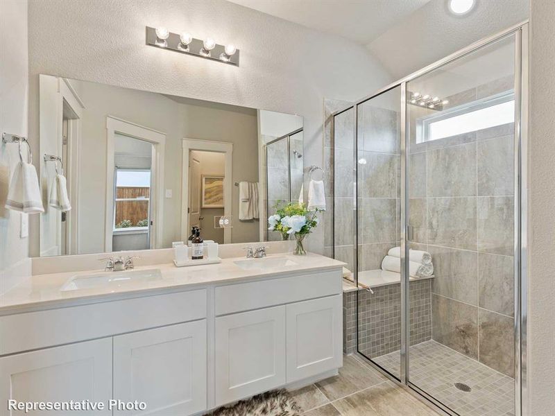 Bathroom with a textured ceiling, vanity, vaulted ceiling, and a shower with shower door