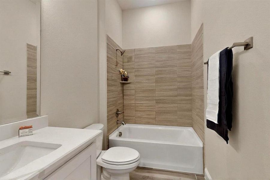 Bathroom featuring  shower combination, toilet, vanity, and wood finished floors