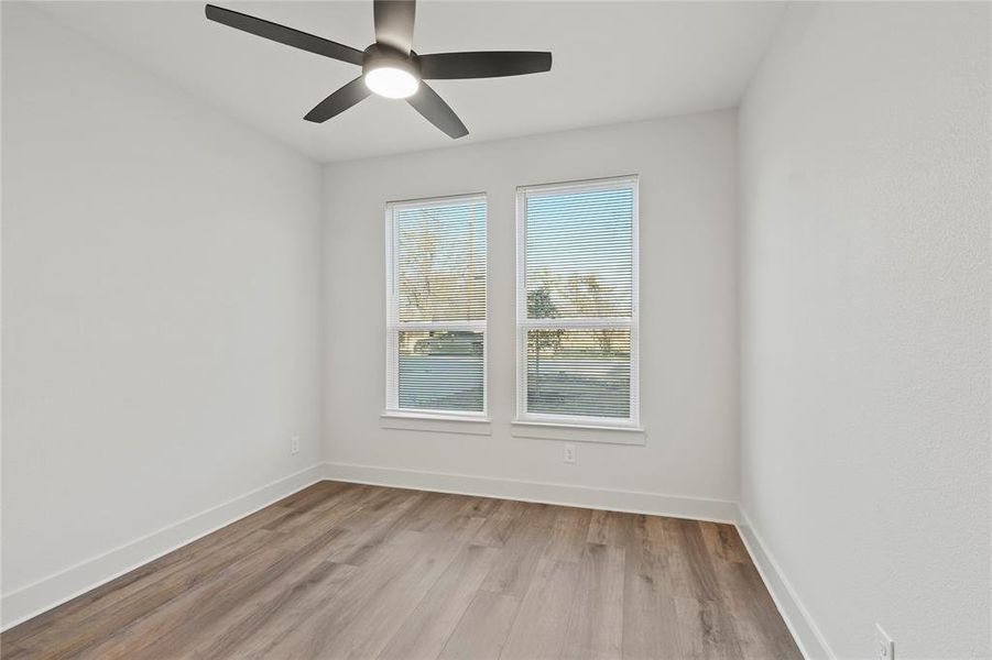 Empty room featuring light wood-type flooring, a ceiling fan, and baseboards