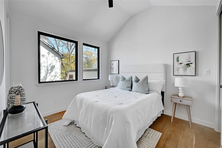 Bedroom with light wood-type flooring, vaulted ceiling, and ceiling fan