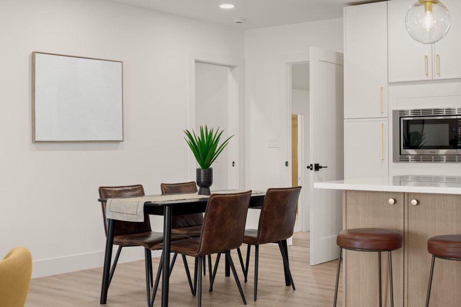 Dining area with light wood finished floors and recessed lighting