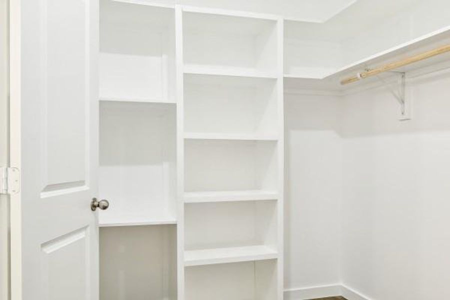 Spacious walk-in closet featuring built-in shelves and ample hanging space for organized storage. Spacious walk-in closet featuring built-in shelves and ample hanging space for organized storage.