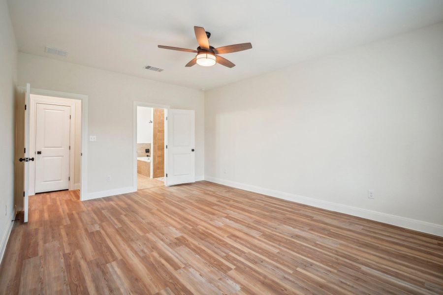 Primary Bedroom featuring visible vents, a ceiling fan, light wood-type flooring, and baseboards
