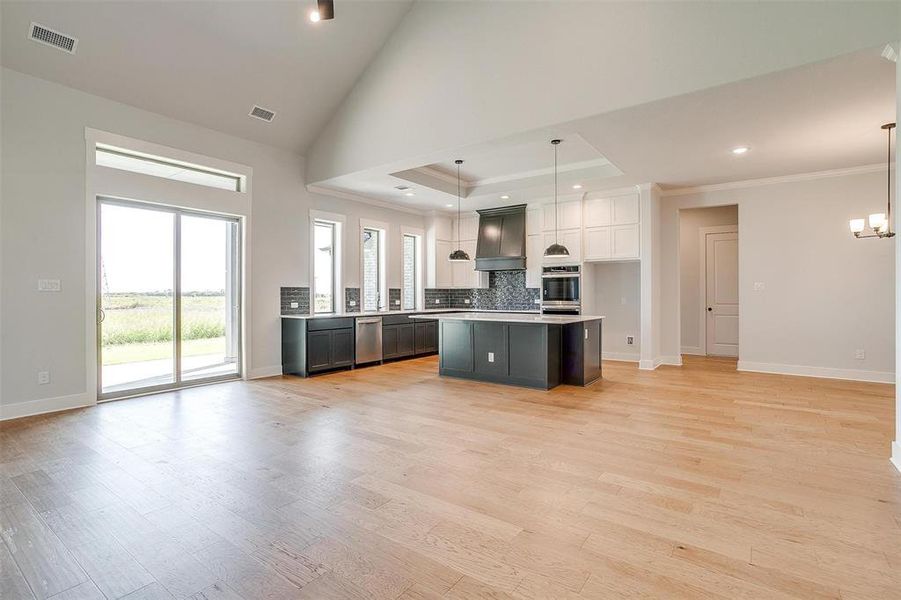 Kitchen featuring ornamental molding, a center island, hanging light fixtures, and light wood-type flooring