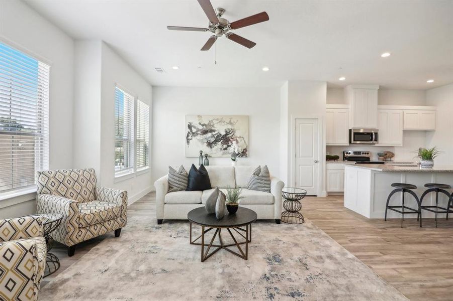 Living room with a wealth of natural light, light hardwood / wood-style flooring, and ceiling fan