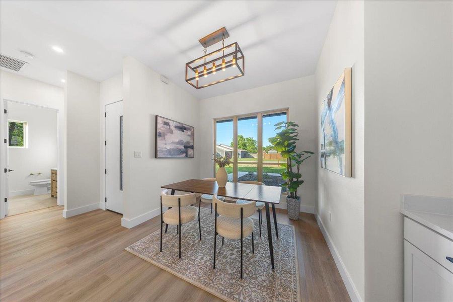 Dining area featuring visible vents, baseboards, light wood-type flooring, and an inviting chandelier