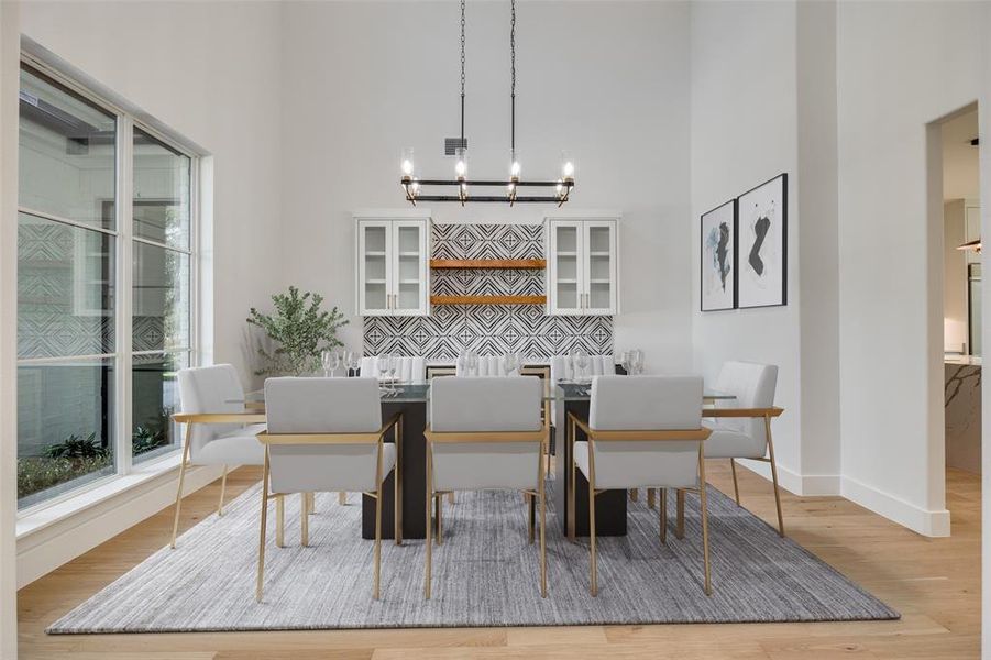 Dining space featuring a high ceiling and light wood-style floors Dining space featuring a high ceiling and light wood-style floors