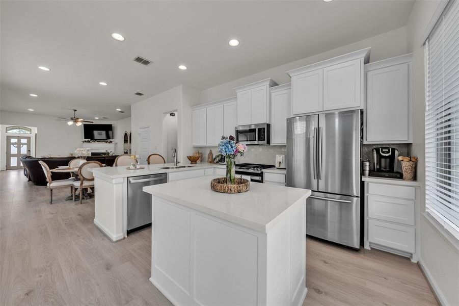 Modern kitchen featuring white cabinetry, stainless steel appliances, a center island, recessed lighting, and wood-finish flooring Modern kitchen featuring white cabinetry, stainless steel appliances, a center island, recessed lighting, and wood-finish flooring