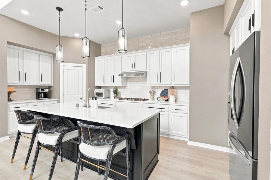 Upgraded backsplash tile carrying above cabinets. Custom hardware on cabinets and drawers. Coffee bar to your left. Walk-in pantry to the left