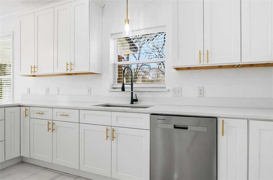 Kitchen featuring dishwasher, white cabinets, decorative light fixtures, and plenty of natural light Kitchen featuring dishwasher, white cabinets, decorative light fixtures, and plenty of natural light
