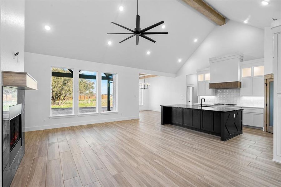 Kitchen featuring a large island, white cabinetry, ceiling fan, custom exhaust hood, and high vaulted ceiling