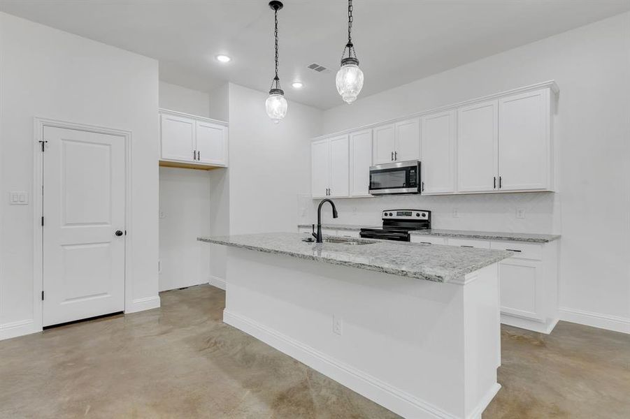 Kitchen with concrete floors, white cabinets, appliances with stainless steel finishes, light stone counters, and hanging light fixtures