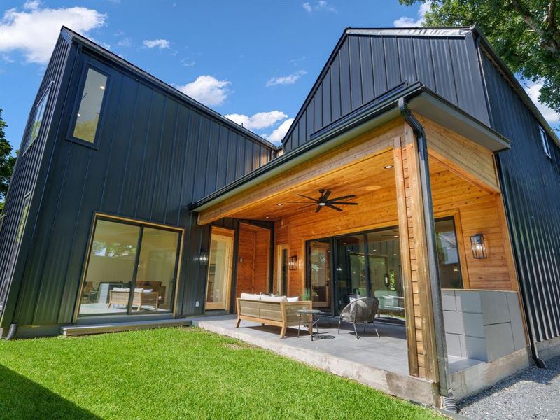 Back of house featuring board and batten siding, a ceiling fan, a patio area, an outdoor hangout area, and a metal roof