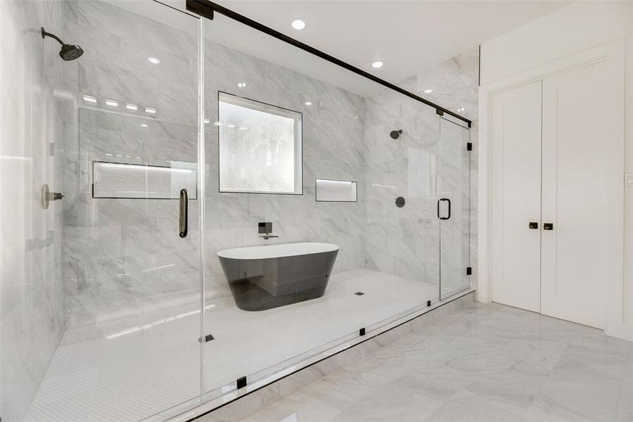 Primary Bathroom featuring a marble tile finish shower, a freestanding soaker bathtub, and light marble finish flooring