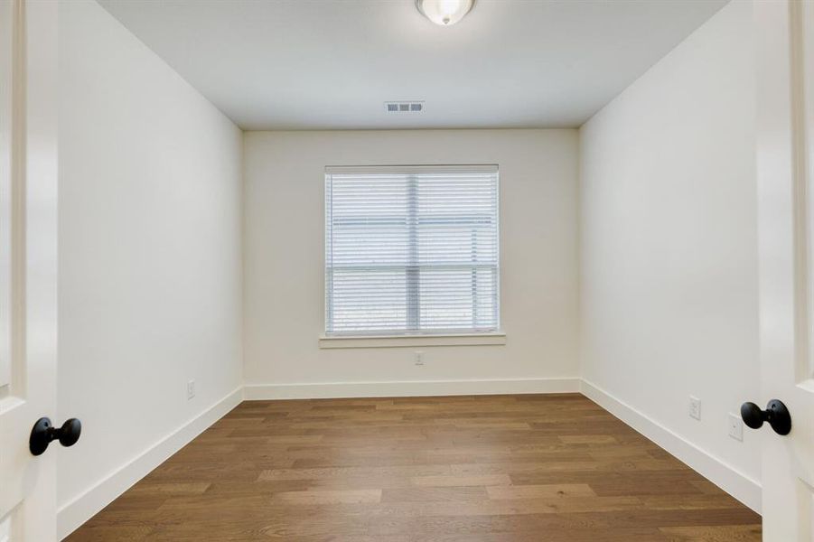Room featuring wood-finish flooring, white walls, and a single window with blinds