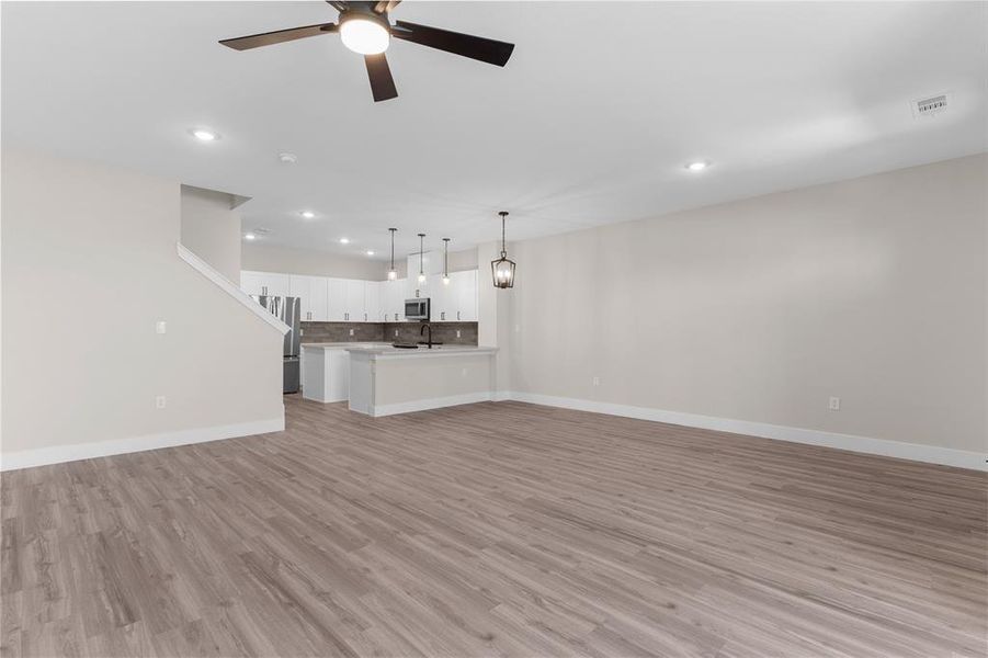 Spacious open-concept living area featuring wood-finish flooring, recessed lighting, and a ceiling fan