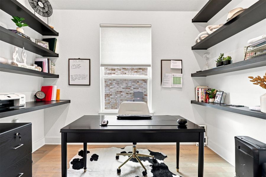 Ample built-in shelving and light wood flooring define this dedicated home office space.