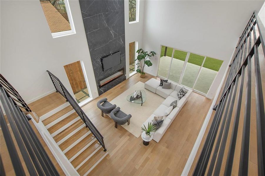 Living room featuring a premium fireplace, a towering ceiling, and hardwood / wood-style floors