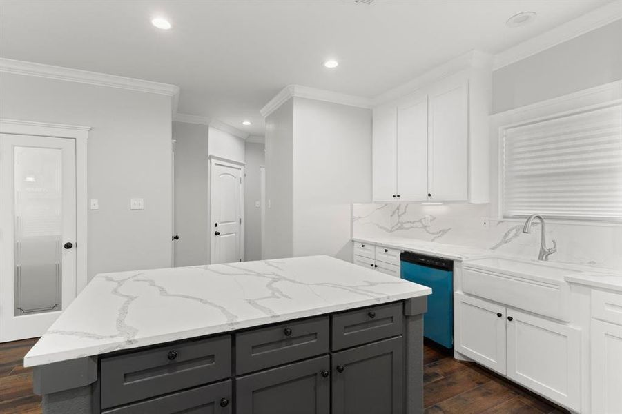 This is a modern kitchen featuring white cabinetry, a contrasting gray island a neutral color palette, creating a sleek and inviting atmosphere.