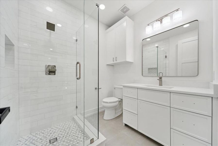 Bathroom with a shower with door, tile patterned floors, toilet, and vanity