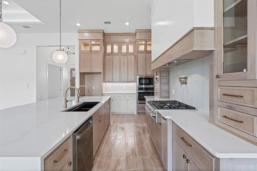 Kitchen with light brown cabinets, a spacious island, light stone counters, tasteful backsplash, and recessed lighting Kitchen with light brown cabinets, a spacious island, light stone counters, tasteful backsplash, and recessed lighting