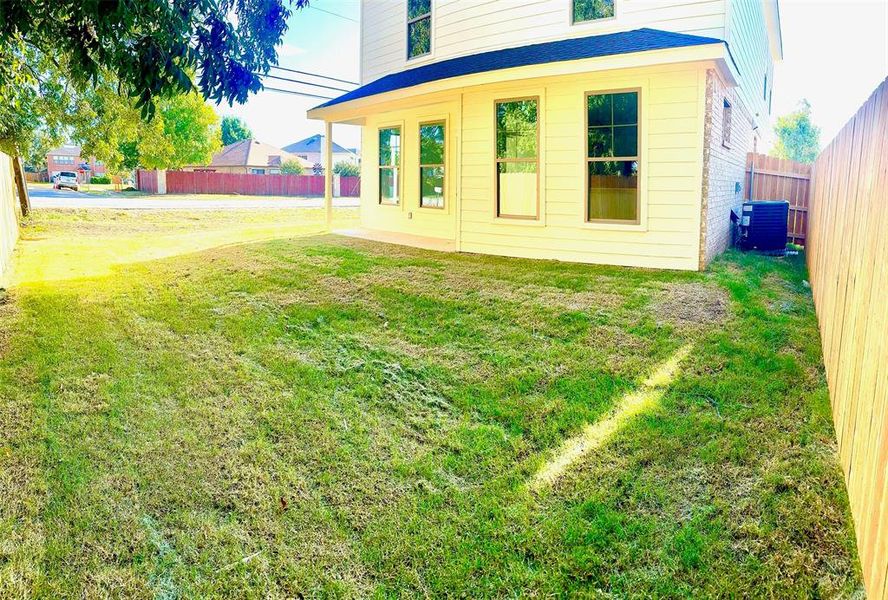 Back of house with central AC and a lawn